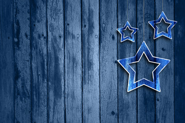 Fototapeta na wymiar Abstract blue wooden background with illustrated glass effect Christmas and New Year Holiday decoration star shapes hanging on string. Xmas decoration with copy space background.