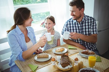 Family toasting a cup of coffee while having breakfast