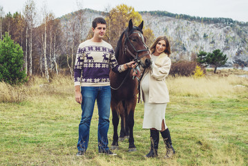 pregnant girl and her husband standing next to the horse