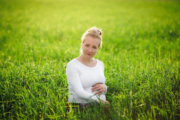 Young pregnant woman embracing her belly at sunset.