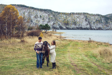 Fototapeta na wymiar pregnant girl and her husband standing next to the horse