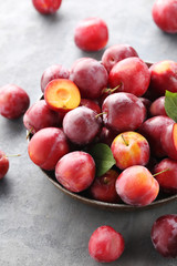 Fresh plums on a grey wooden table