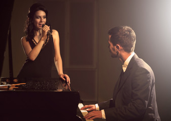 Young couple posing near piano in the dark © Africa Studio
