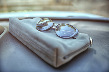 Woman bag with sunglasses on car panel, closeup
