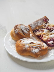 Mix of pastries. Homemade buns on white plate. Selective focus on the front.