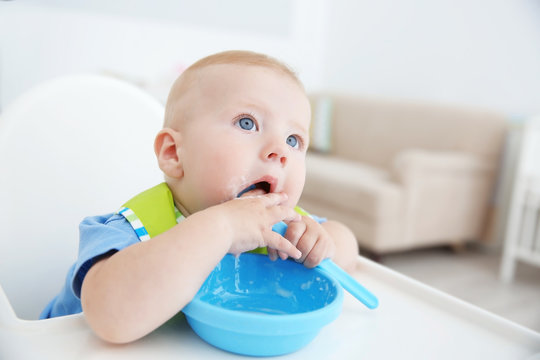 Little baby eating from bowl in kitchen