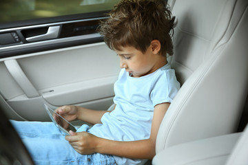 Fototapeta na wymiar Boy playing with tablet in car