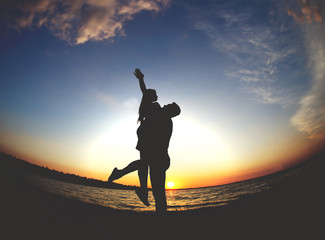 Young couple in love having fun on the beach at sunset