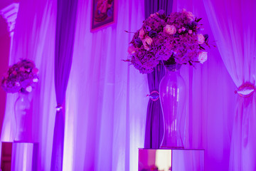 Crystal vase with bouquets stand in violet lights