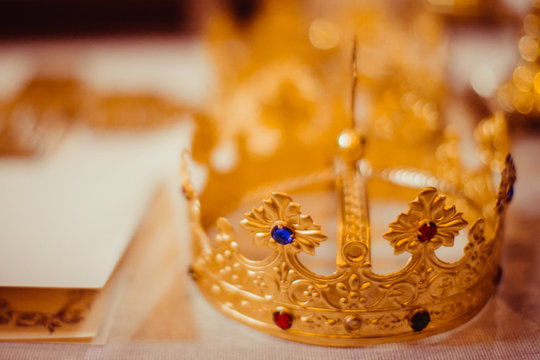 Golden crown with precious stones stands on the white table