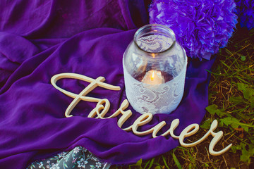 Wooden lettering Forever lies on the violet cloth in the garden
