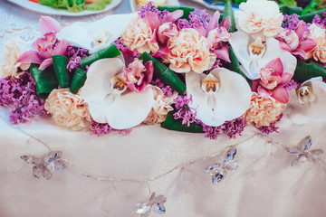 White orchids put in a flower garland lying on the dinner table