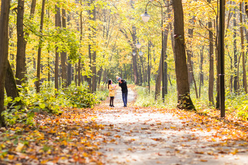 Fototapeta premium happy young family with their daughter spending time outdoor in the autumn park.