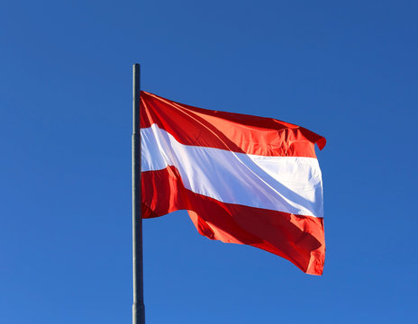 Austrian flag waving in the blue cloudless sky