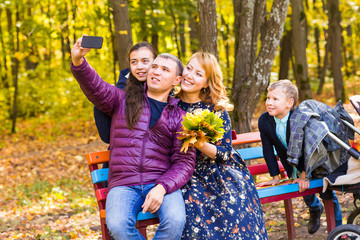Smiling young family taking selfies on an autumns day