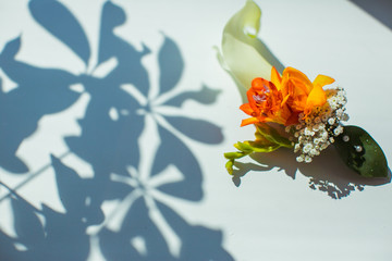 Orange boutonniere lies on the white table outside