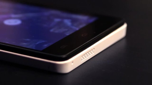The white smartphone vibrates at a black table close up