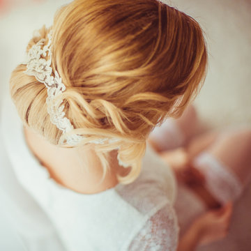 Blonde bride with hair up adjusts her garter