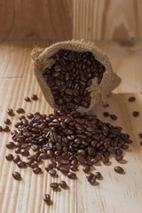 Coffee beans  in a bag on wooden background