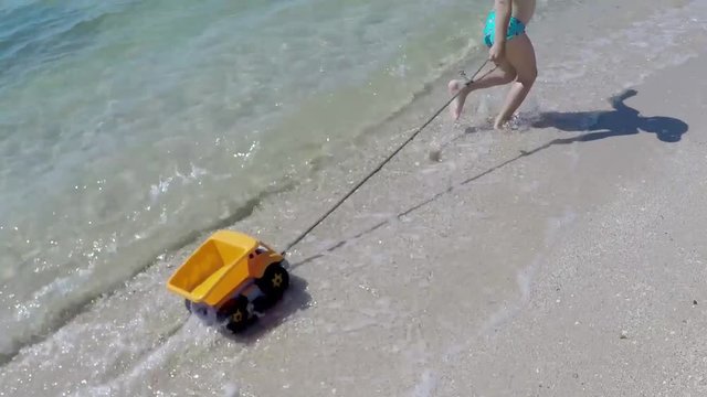 Happy Boy Running Along Beach with Toy Truck