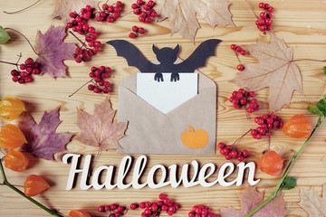 Top view of a Halloween wooden desk top with paper, envelope, bat, berries and maple leaves. With copy space