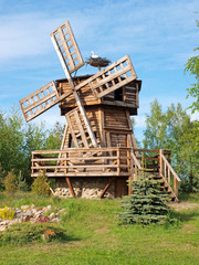 Decorative wooden windmill in park and stork in the nest 2