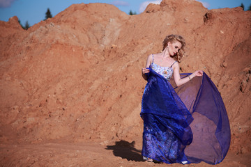 Portrait of a beautiful girl in a blue dress with handkerchief sand sky