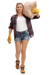 Female farmer walking and carrying a burlap sack