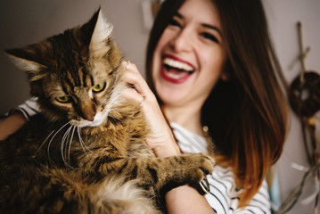 stylish hipster woman playing with her cat in modern room