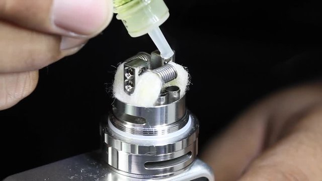 dripping e juice e liquid to new dual kanthal micro coils and organic cotton on atomizer&rsquo;s deck base of electronic cigarette for vaping, close up scene, high definition, Full HD, 1920x1080