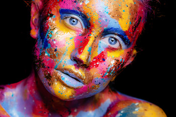 Portrait of a woman with colorful paint brushstroken on face. Bright blue eyes. Advertising Space