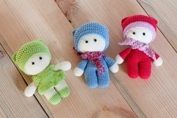 Three variegated crochet soft toys on a wooden background