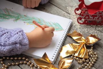 child writes letter to Santa and draw a Christmas tree.
