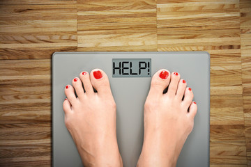 Time to start a diet with women’s feet on a scale, saying HELP - obrazy, fototapety, plakaty