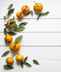 Fresh tangerines with leaves on white wooden background copy space for product or text top view vertical