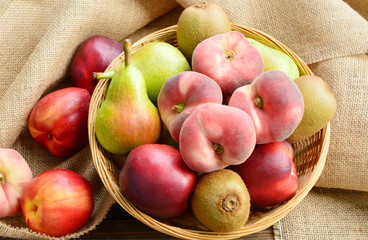 Dough nut peach,European Pear,Kiwifruit,nectarines in basket on sack cloth back ground.
a variety of fruits in summer.
