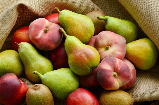 Dough nut peach,European Pear,Kiwifruit,nectarines in basket on sack cloth back ground.
a variety of fruits in summer.
