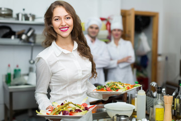 Female waiter taking dish at kitchen