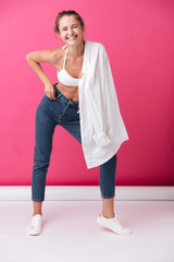 Young woman in cheerful clothes holding shirt on her shoulder