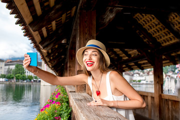Young female traveler making selfie portrait on the old bridge in Lucerne city. Having great...