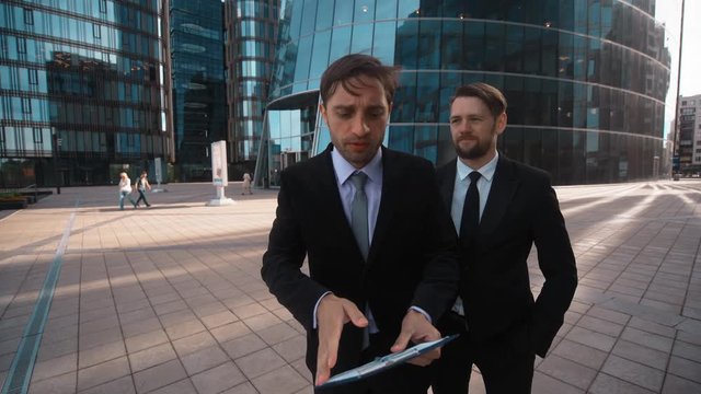 4k. Ultra HD. POV. Two young successful attractive business competitors try to make You offer. They interrupt themselfs. Be the main and first in all concept. Businessmen. Male. Formal suit, tie, teal