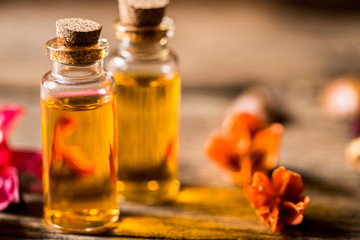 bottle of aroma essential oil or spa and natural fragrance oil with dry flower on wooden table, image for aroma spa alternative therapy medicine and meditation aroma concept.
