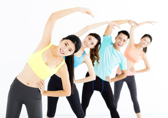 smiling young fit group stretching in gym