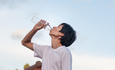 Man drinking water from bottle outside,soft focus.