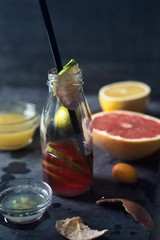 Half-empty bottle with citrus juice on the dark stone background