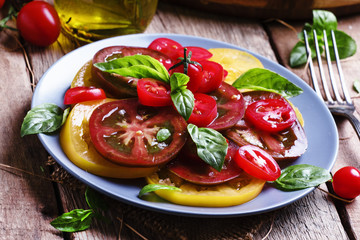 Salad of colorful tomatoes on plate. Vintage wooden background,