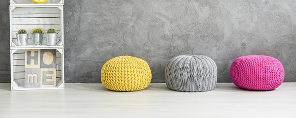 Colorful poufs and a shelf against a grey wall