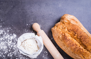 Fresh bread and flour top view on dark background copy space.