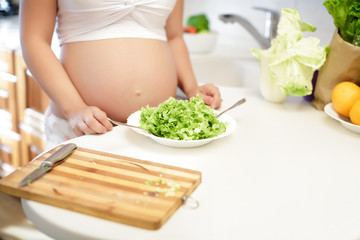 Obraz na płótnie Canvas pregnant young woman mixing salad in a bowl