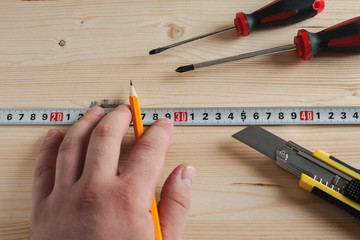 Hand with pencil and measuring tape making marks